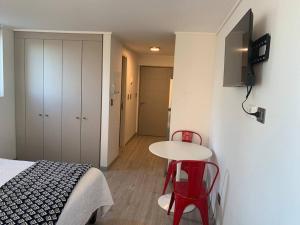 a room with a bed and a table and two red chairs at Departamento studio. in Temuco