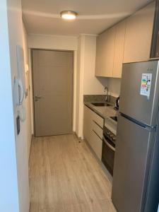 a kitchen with a stainless steel refrigerator and a door at Departamento studio. in Temuco