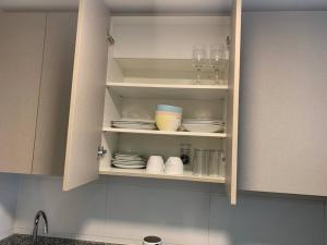 a kitchen cabinet with plates and wine glasses and dishes at Departamento studio. in Temuco +3 photos
