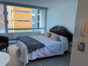 a bedroom with a bed and a large window at Departamento studio. in Temuco