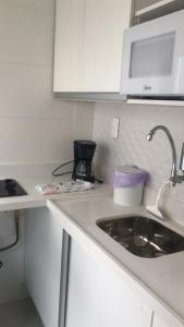 eine weiße Küche mit einer Spüle und einer Mikrowelle in der Unterkunft Lindo Apartamento Copacabana in Rio de Janeiro