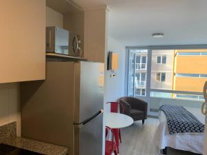 a kitchen with a refrigerator and a table in a room at Departamento studio. in Temuco