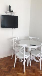 a white table and chairs with a tv on a wall at Lindo Apartamento Copacabana in Rio de Janeiro