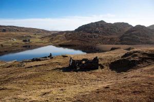 un viejo edificio en una colina junto a un lago en No1 Dalbeg, a Hebridean Escape and your Adventure., 