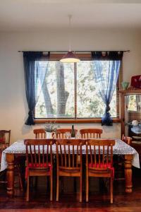 un comedor con una mesa con sillas y una ventana en The Black Cockatoo - Secret Garden Treetops Home, en Katoomba