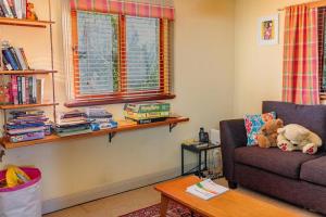 a living room with a couch and a shelf with books at The Black Cockatoo - Secret Garden Treetops Home in Katoomba