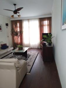 a living room with a white couch and a ceiling fan at Apartamento Gonzaga Santos in Santos