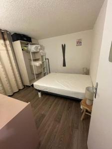 a small room with a bed and a wooden floor at Appt chaleureux 2 - 4 personnes au pied des pistes - draps et linges de toilette non fournis - ménage non inclus - attention rénovation de façade actuellement in La Mongie