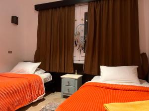 una camera con due letti con lenzuola arancioni e una finestra di South Marina Apartment Wi-Fi available a Hurghada