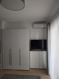 a living room with white cabinets and a television at Studio apartman Implex in Đakovo