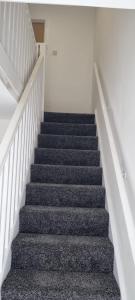 a staircase in a building with grey carpet at Cheerful 3-bedroom home in Sale - free parking on premises in Sale