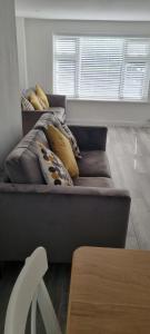 a couch with pillows on it in a living room at Cheerful 3-bedroom home in Sale - free parking on premises in Sale