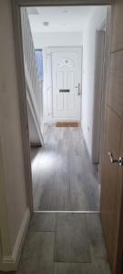 an empty hallway with a white door and a staircase at Cheerful 3-bedroom home in Sale - free parking on premises in Sale