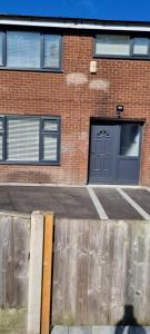 un bâtiment en briques avec une porte bleue et une clôture dans l'établissement Cheerful 3-bedroom home in Sale - free parking on premises, à Sale