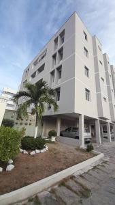 a large white building with a palm tree in front of it at Apartamento Bonavides in Fortaleza