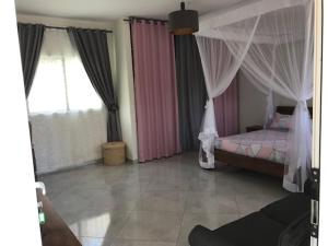 a bedroom with a canopy bed and curtains at L' Oasis de Verdure in Antananarivo