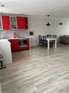 a kitchen with red cabinets and a table and chairs at Annas ielas apartamenti in Valmiera