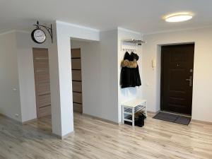 a hallway with a black door and a clock on a wall at Annas ielas apartamenti in Valmiera