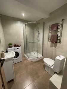 a bathroom with a shower toilet and a washing machine at Annas ielas apartamenti in Valmiera