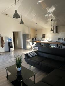 uma sala de estar com um sofá preto e uma cozinha em LAubergerie de Lastours em Coursan