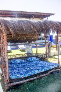 une cabane en paille avec un lit bleu dans l'herbe dans l'établissement Beach Suites Villa Drisana, à Barra de Camaratuba