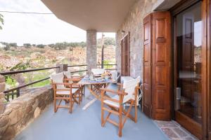 eine Terrasse mit einem Tisch und Stühlen auf dem Balkon in der Unterkunft Stone Sunset Villa in Sfendoúrion