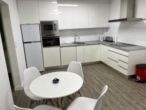 a white kitchen with a white table and chairs at Apartamento en la playa. Free Parking. Free WiFi in L'Escala