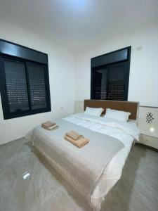a bedroom with a large bed with two towels on it at Alfred Apartments in Ramallah