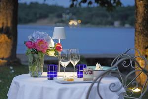 une table avec un vase de fleurs et des verres à vin dans l'établissement Hotel Ristorante Lepanto, à Salò
