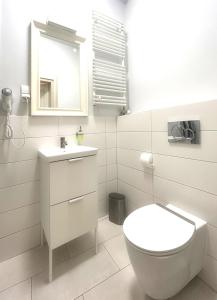 a white bathroom with a toilet and a mirror at Old Town Apartment in Krakow