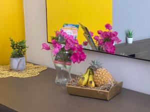 un vase avec des fleurs et une boîte de fruits sur une table dans l'établissement PETIT COIN DE PARADIS, à Saint-François