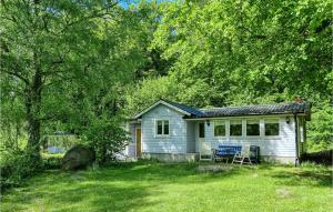 ein blaues Haus mit einem Tisch und Stühlen im Hof in der Unterkunft Awesome Home In Fjlkinge With Kitchen in Fjälkinge