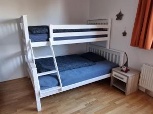 een slaapkamer met 2 stapelbedden en een houten vloer bij Forest View, 2-floor Apartment in Hočko Pohorje