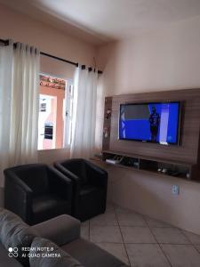 uma sala de estar com uma televisão de ecrã plano e um sofá em Casa em Bombinhas zimbros em Bombinhas
