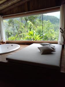 uma cama num quarto com uma grande janela em Pousada Flor de Lótus dos Canyons em Praia Grande