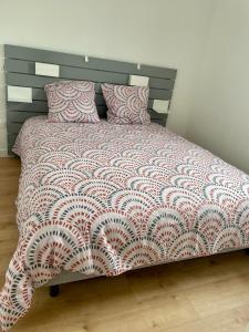 uma cama com um edredão e almofadas vermelhos e brancos em PENTY em Porsmilin