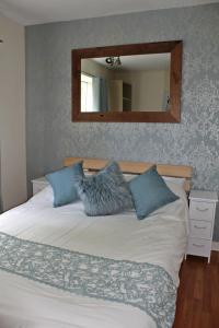 a bed with two pillows and a mirror on the wall at Boswell-Large Balcony Apartment-Town & Racecourse in Doncaster