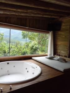 uma banheira num quarto com uma grande janela em Pousada Flor de Lótus dos Canyons em Praia Grande