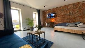 sypialnia z ceglaną ścianą, łóżkiem i kanapą w obiekcie Apartamenty Gliwice Staromiejska 65 w mieście Gliwice