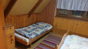 niewielka sypialnia z łóżkiem i oknem w obiekcie Chata na Plantáži w Habówce