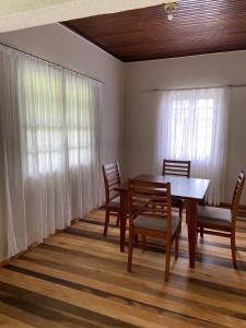 ein Esszimmer mit einem Tisch, Stühlen und einem Fenster in der Unterkunft Recanto Luigi in Rio dos Cedros