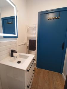 La salle de bains est pourvue d'un lavabo blanc et d'une porte bleue. dans l'établissement La Baie L’Etoile, Apt 4 pers, bord de mer, parking privé, Fort Mahon Plage, à Fort-Mahon-Plage