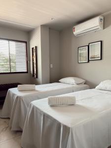 Habitación con 3 camas y sábanas blancas. en Pousada Minha Praia, en João Pessoa