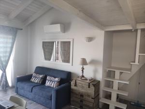 een woonkamer met een blauwe bank en een trap bij Attico IL SOLE in Castelsardo