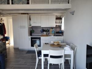 een keuken met witte kasten en een tafel en stoelen bij Attico IL SOLE in Castelsardo
