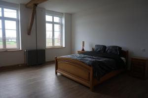 a bedroom with a bed and two windows at La Ferme Décroué 