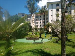a park with a bench and palm trees and buildings at Apartamento Condomínio Wembley Tênis - Toninhas - Ubatuba - SP in Ubatuba