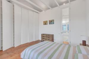 a white bedroom with a striped bed and a window at Stunning Shoreditch Loft Warehouse Style Apartment in London