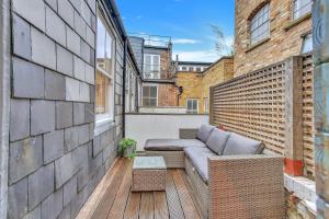 einen Balkon mit einem Sofa und einem Tisch auf einem Gebäude in der Unterkunft Stunning Shoreditch Loft Warehouse Style Apartment in London