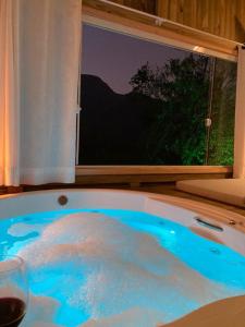 uma banheira cheia de água azul ao lado de uma janela em Pousada Flor de Lótus dos Canyons em Praia Grande